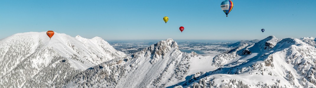 Farbenfrohe Heißluftballons über der verschneiten Bergwelt – das Ballonfestival im Tannheimer Tal verwandelt den Winterhimmel in ein faszinierendes Panorama.
