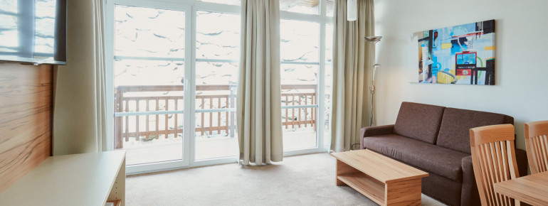 Der Wohnbereich besteht aus einer Sitzecke, einem Sofa, einem TV und dem Balkon.