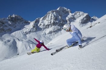 Sowohl Snowboarder als auch Skifahrer finden im Skigebiet Corviglia ihre Lieblingspisten. Hier zwei Wintersportler bei der Abfahrt mit dem Piz Albana und dem Piz Julier im Hintergrund.